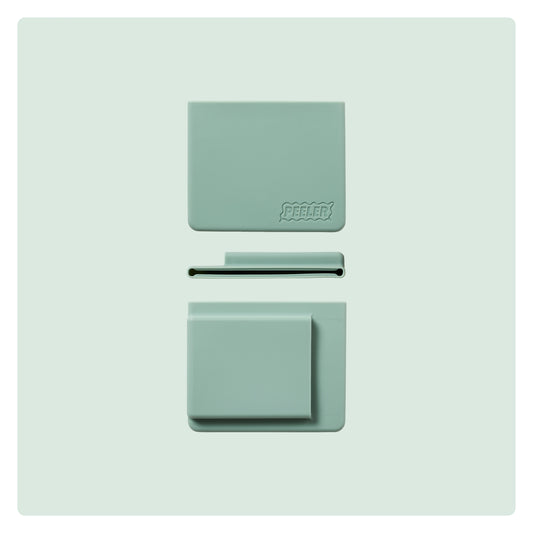 A sage-green silicone slim wallet laid flat, showing the front, side and back with the 'Peeler' logo embossed in the corner.